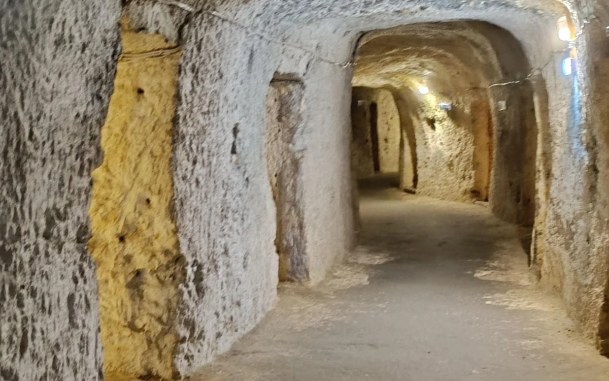 A lit passage cut into soft rock, with openings on both sides