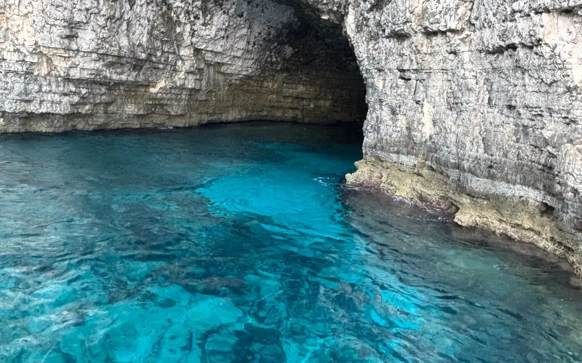 Clear turquoise water running into a limestone sea cave