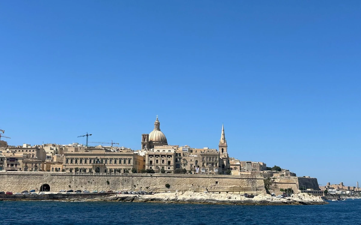 Valletta seen from the water: a church dome and a spire above a long bastion wall