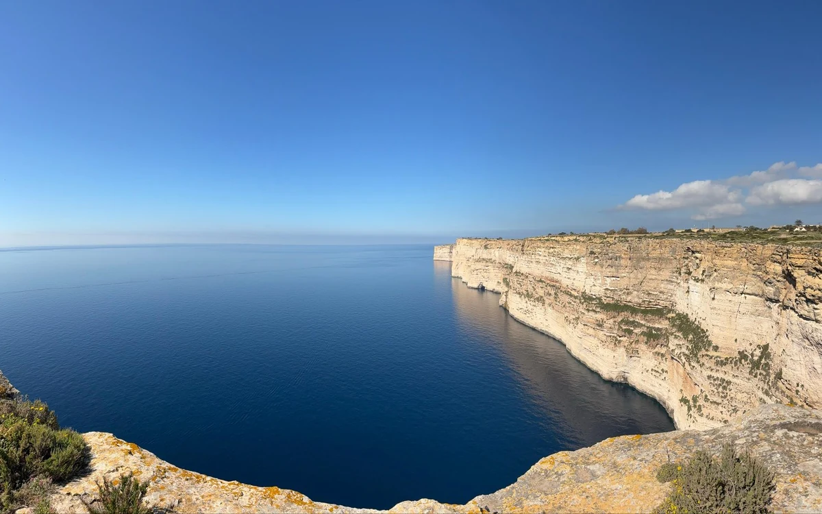 Steile helle Klippen, die ins tiefblaue Meer abfallen, von der Klippenkante aus gesehen