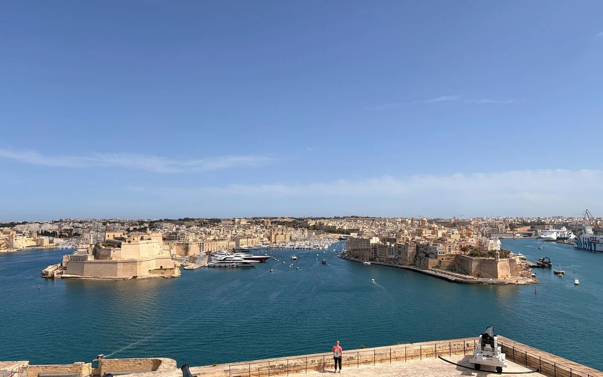 Der Grand Harbour von einer hohen Bastionsterrasse aus gesehen, ein Fort am Wasser gegenüber der Bucht und eine Kanone auf der Terrasse darunter