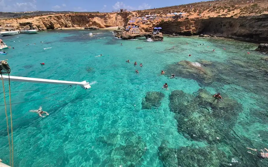 Schwimmer im türkisfarbenen Wasser einer Lagune, vom Deck eines Bootes aus gesehen