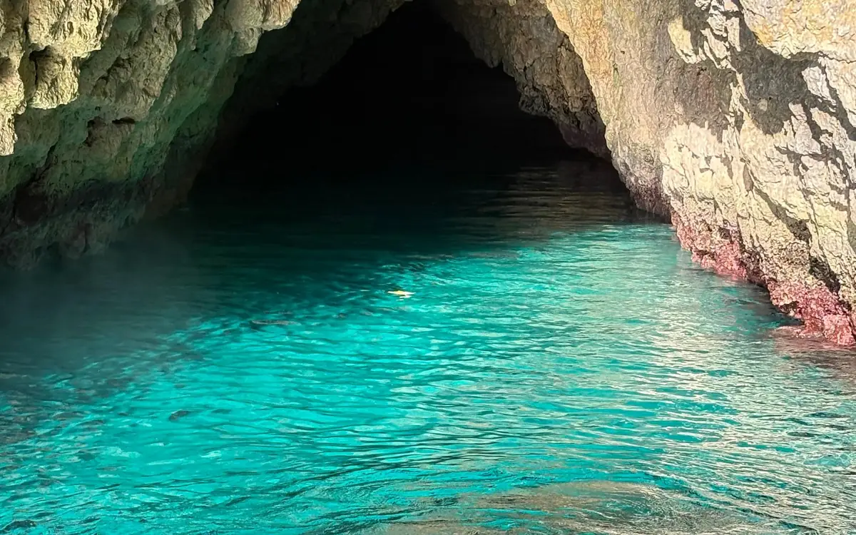 Klares blaugrünes Wasser in einer Meereshöhle, mit dem Felsen, der sich darüber wölbt